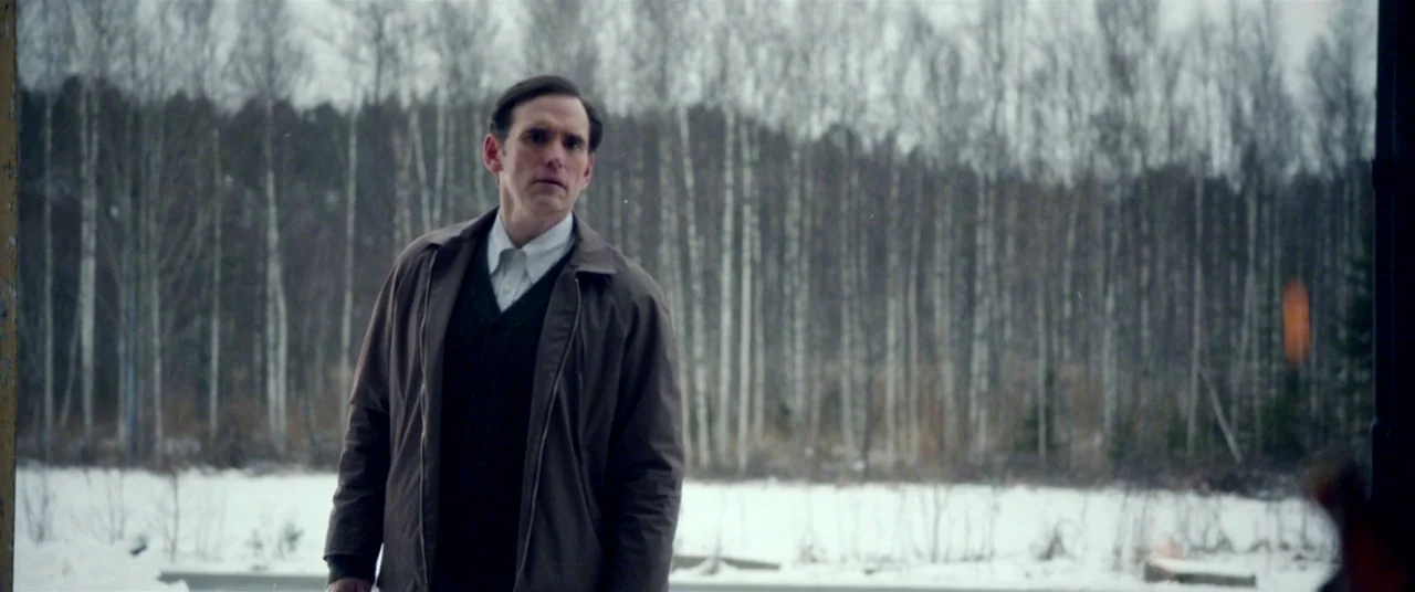 The House That Jack Built (2018) movie still: medium — A man stands in front of a dense forest of thin birch trees. Snow covers the ground during an…