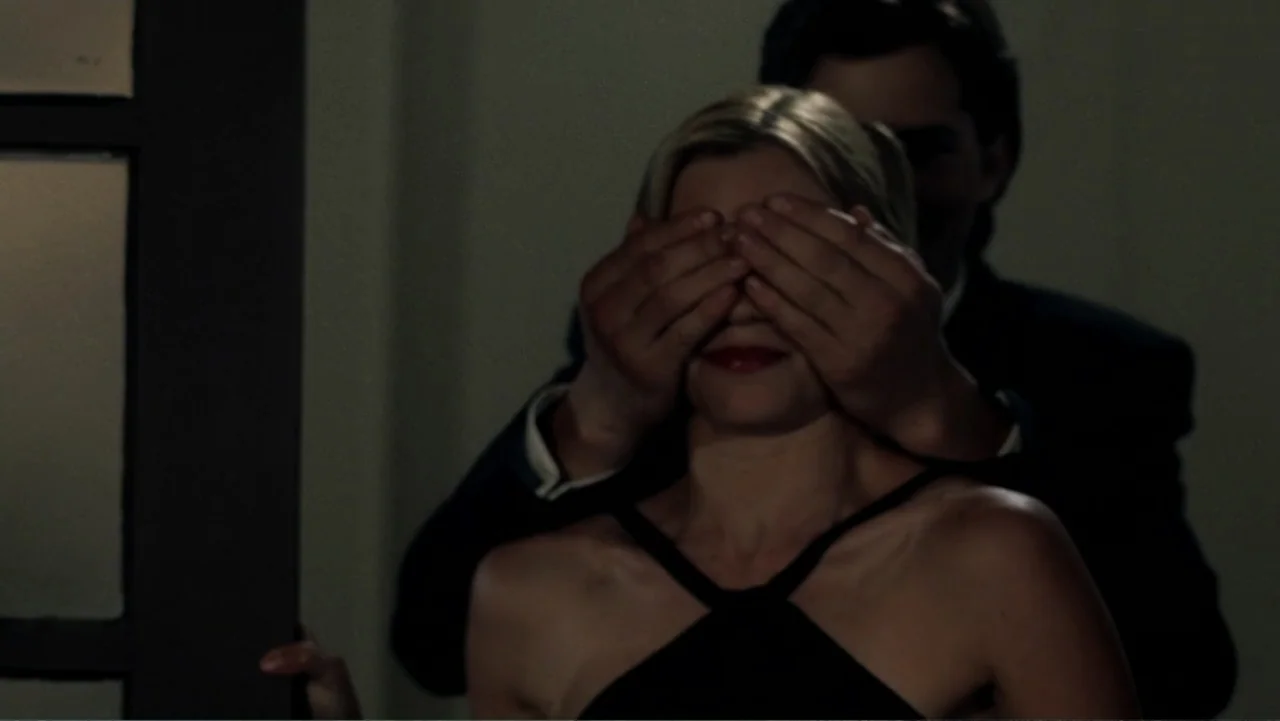 The Butterfly Effect (2004) movie still: medium — A dimly lit interior space with a door frame visible on the left. A man in a dark suit stands…