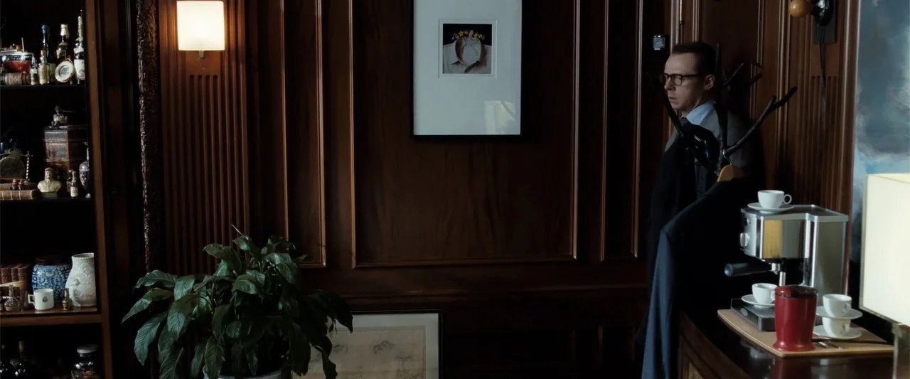 Hector and the Search for Happiness (2014) movie still: medium — A wood-paneled room contains shelves with bottles and a framed artwork on the wall.…