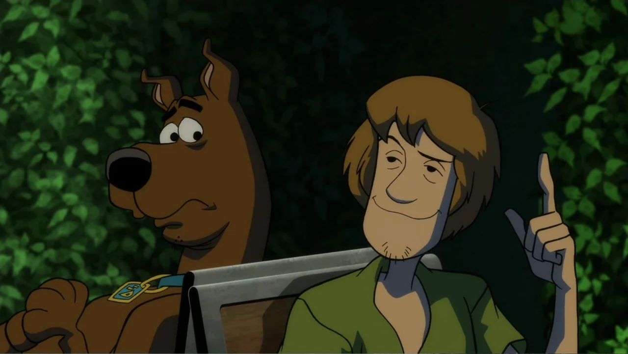 Scooby-Doo! and the Gourmet Ghost (2018) movie still: medium — A dark outdoor space with dense foliage surrounding a wooden park bench. A man in a…
