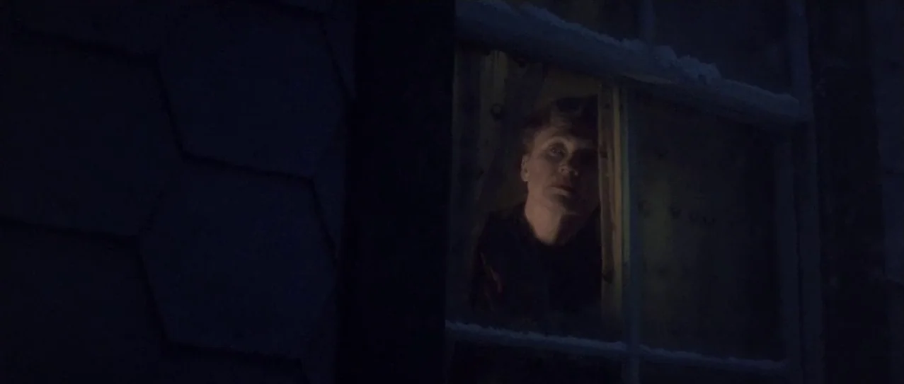 Snow Falling on Cedars (1999) movie still: medium — The exterior of a house at night is partially visible with dark siding. A person is seen looking…