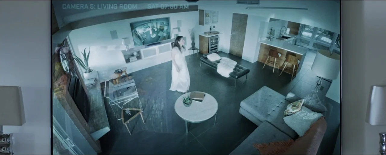 Hostages (2017) movie still: wide — A modern open-plan home interior features polished floors and minimalist furniture. A woman in a white dress…