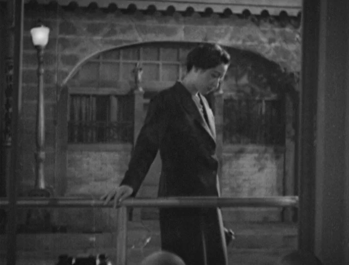 No Regrets for Our Youth (1946) movie still: medium — A night exterior showing a stone walkway with a streetlamp and a metal railing. A woman in a…