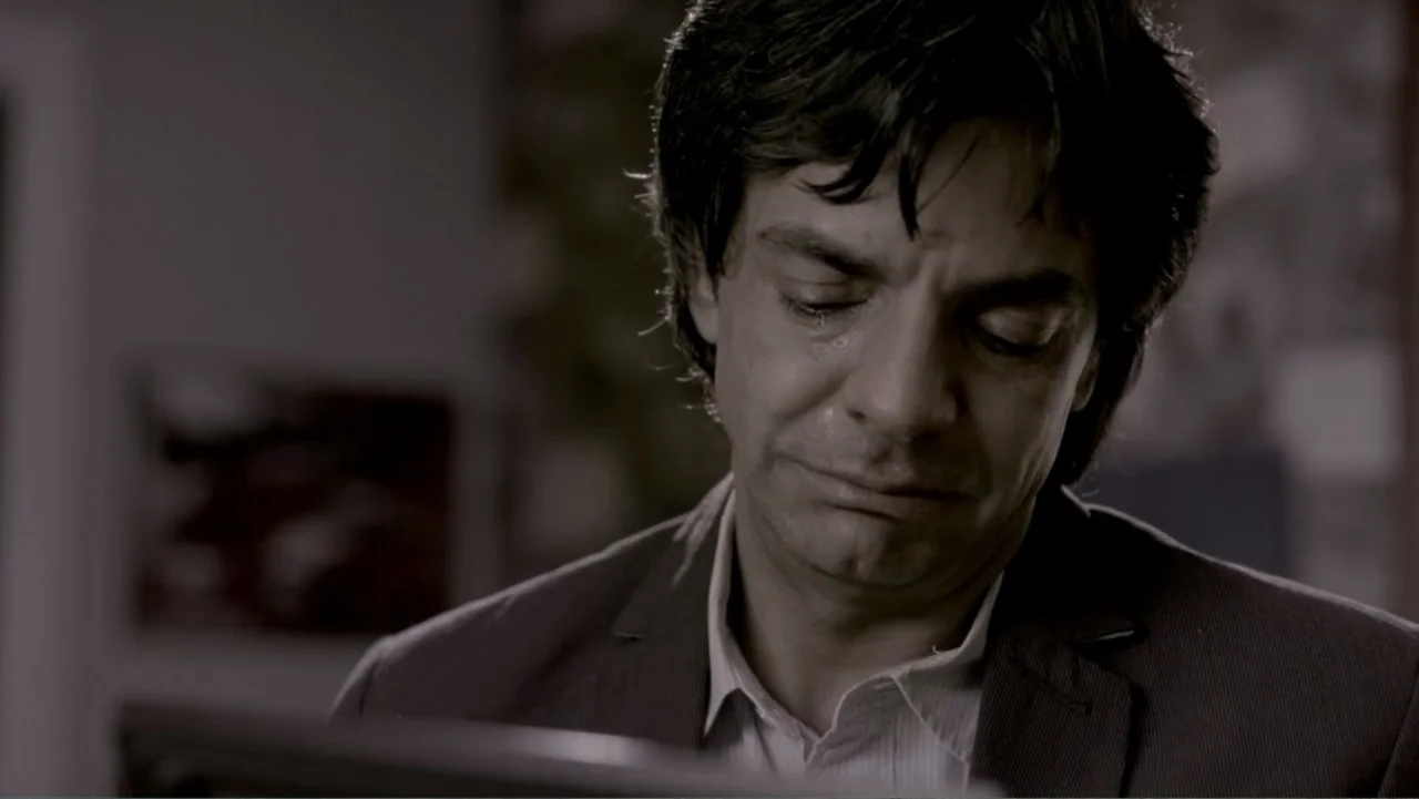 George Lopez: It's Not Me, It's You (2012) movie still: closeup — An interior office space with blurred background details and soft lighting. A man…
