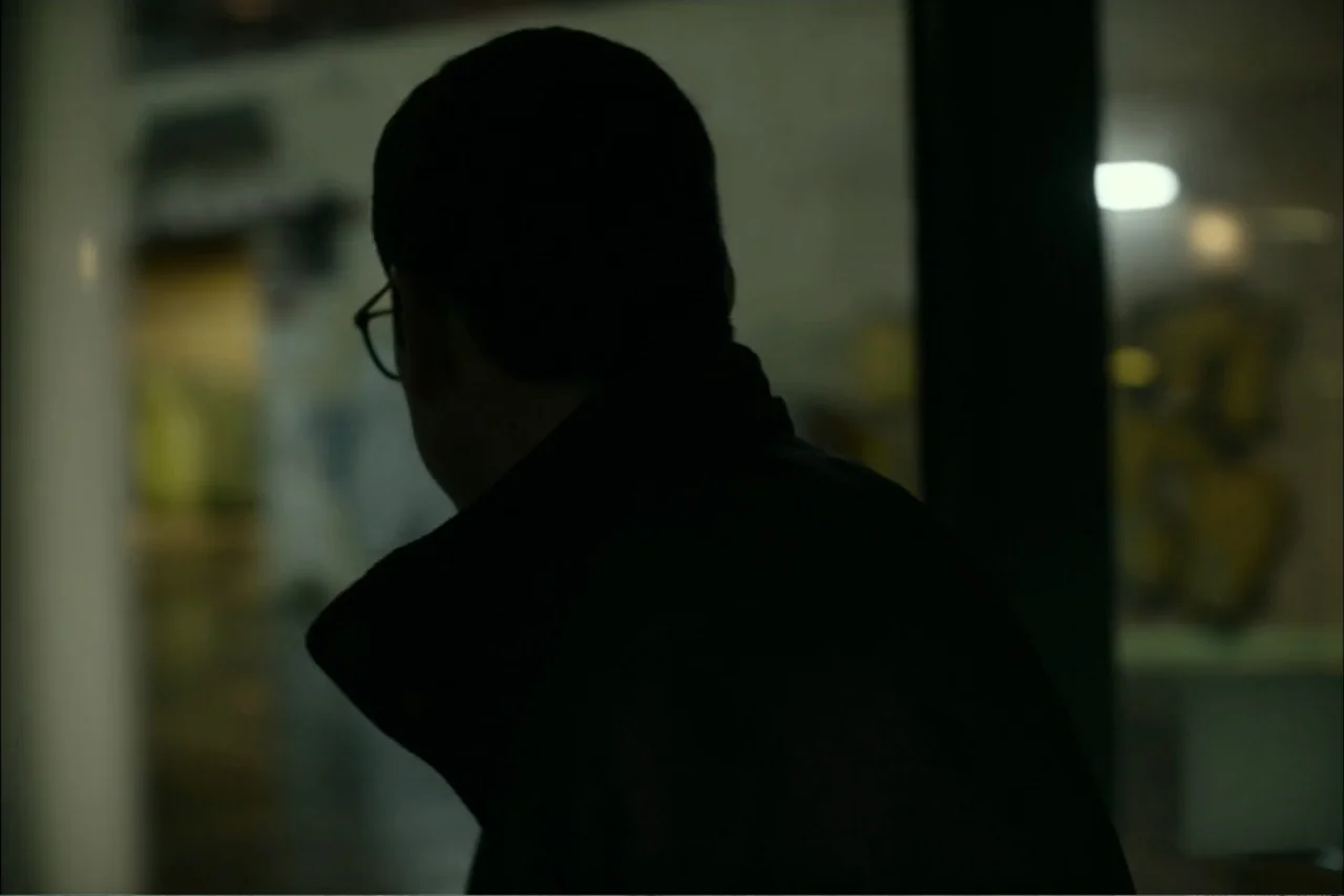 Cross the Line (2020) movie still: medium — A dark interior hallway of a building features a silhouette of a person. The subject stands in shadow…