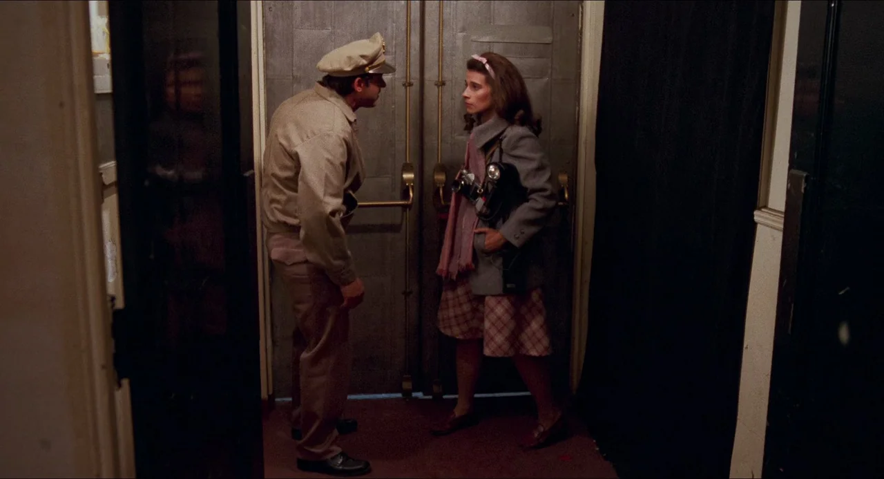 I Wanna Hold Your Hand (1978) movie still: fullbody — A dark hallway leads to a pair of large, metallic double doors with exit handles. A man in a…