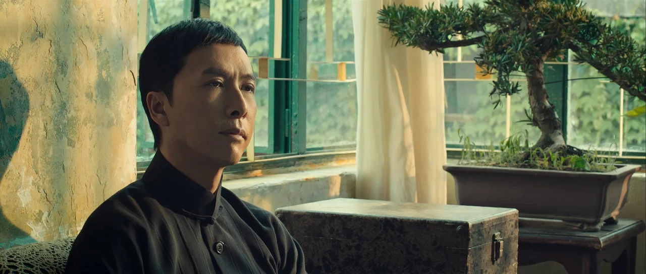 Ip Man 3 (2015) movie still: medium — A quiet indoor space features weathered walls and a window with green-painted metal frames. A man in a dark…
