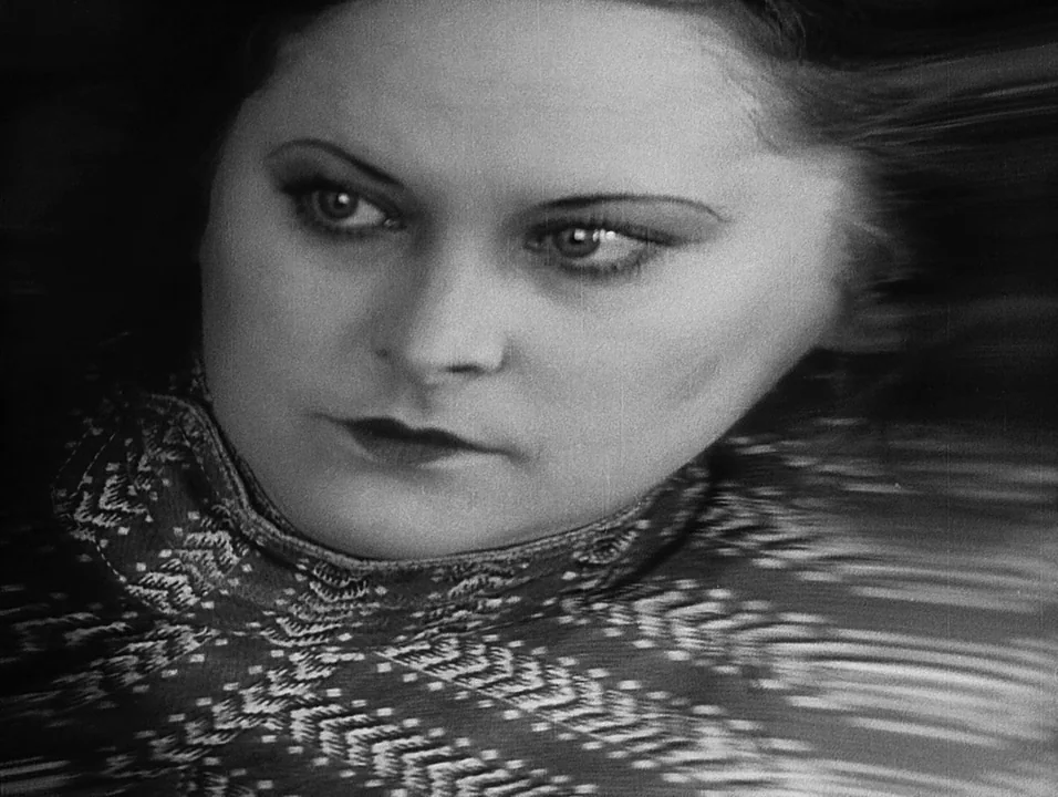 Coeur Fidele (1923) movie still: closeup — A close-up portrait of a woman in a high-necked patterned sweater. The background is blurred and…