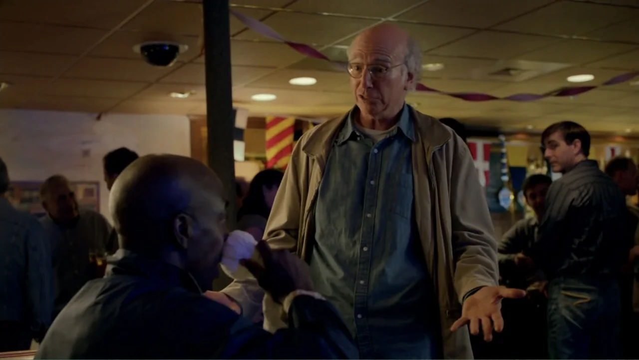 Clear History (2013) movie still: medium — A dimly lit dining area features ceiling decorations and several seated patrons in background. An older…