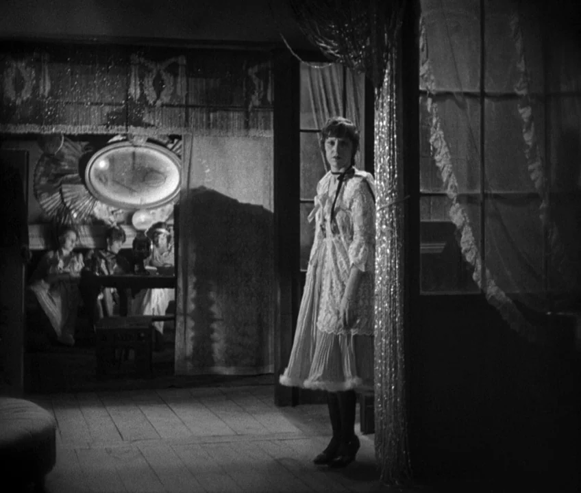 The Threepenny Opera (1931) movie still: fullbody — An interior space features a dark room visible through a doorway with decorative curtains. A…