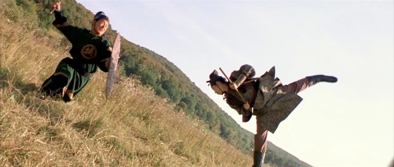 House of Flying Daggers (2004) movie still: fullbody — An open, dry grassy hillside slopes upward against a bright, clear sky. Two individuals in…