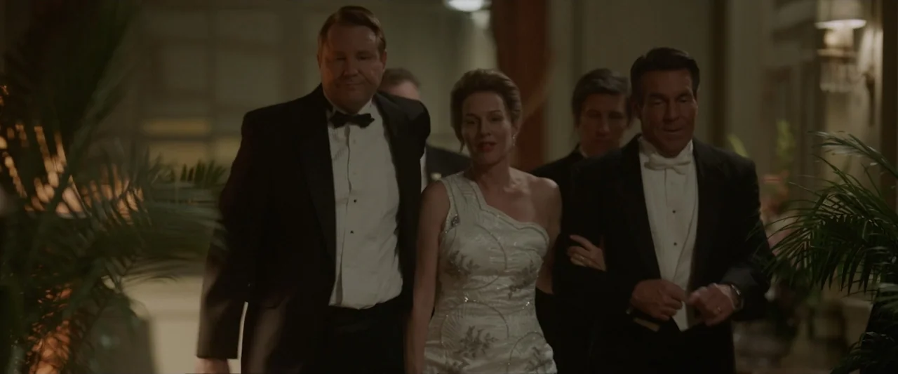 Reagan (2024) movie still: medium — An opulent hotel corridor features dim lighting and decorative potted palm trees. Three adults in formal attire…