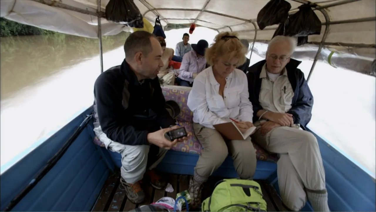 Aliens Inside Us (2013) movie still: medium — A group of people travel in a covered boat along a murky river. Three individuals sit on a bench seat…