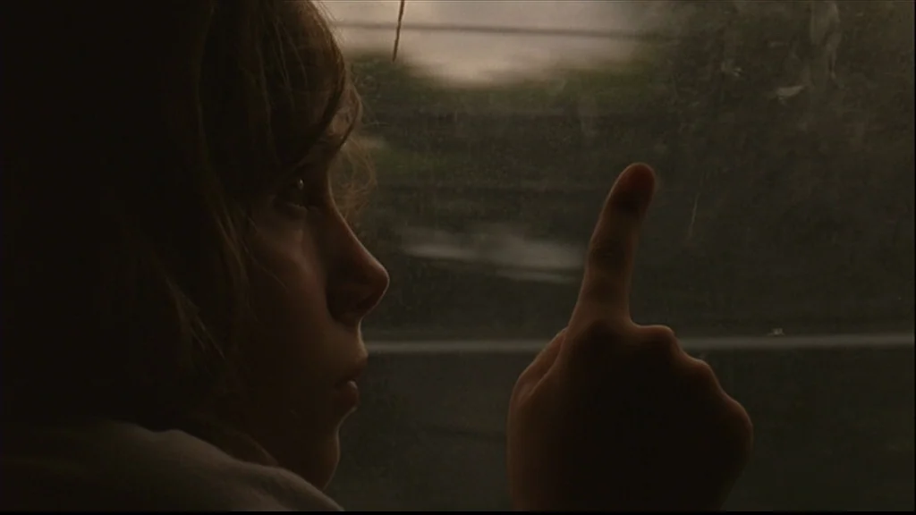 Margot At The Wedding (2007) movie still: closeup — A person sits beside a smudged window inside a moving vehicle. The person points a finger at the…