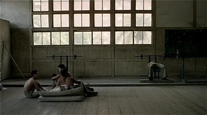 A Time To Love and A Time To Die (1985) movie still: wide — A spacious room features wooden floors and a large multi-paned windowed wall. Three…