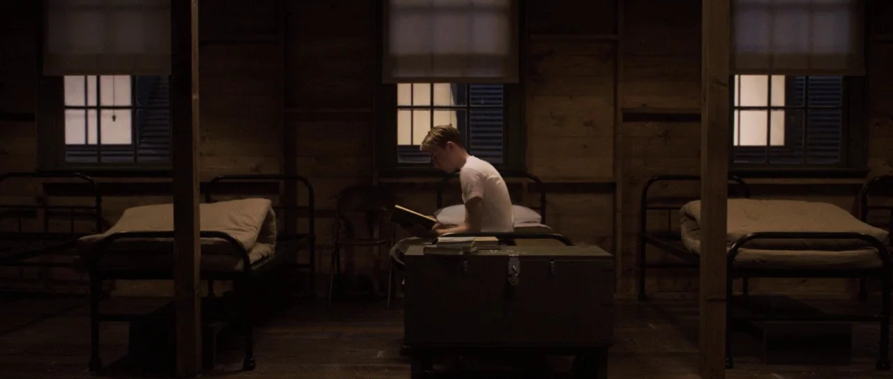 Captain America: The First Avenger (2011) movie still: wide — A dimly lit wooden military room contains rows of simple iron cots. A single soldier…