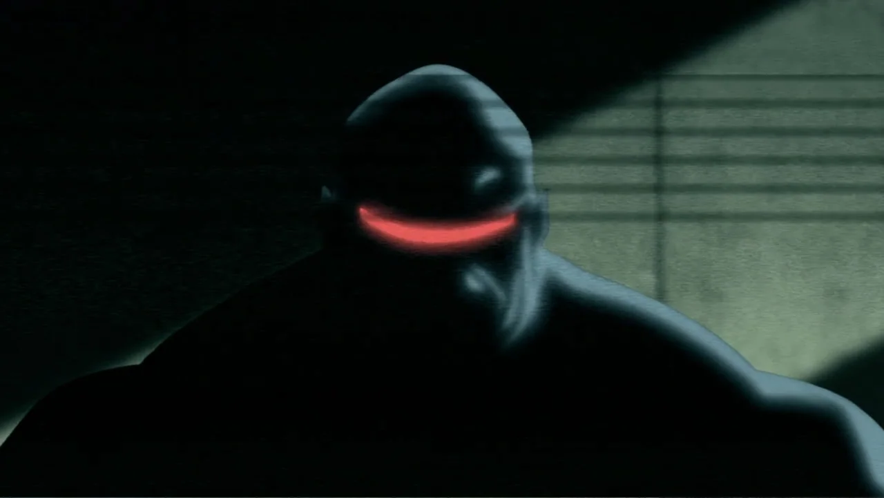 Batman: The Dark Knight Returns, Part 1 (2012) movie still: closeup — A dark, dimly lit indoor space with horizontal paneling in the background. A…
