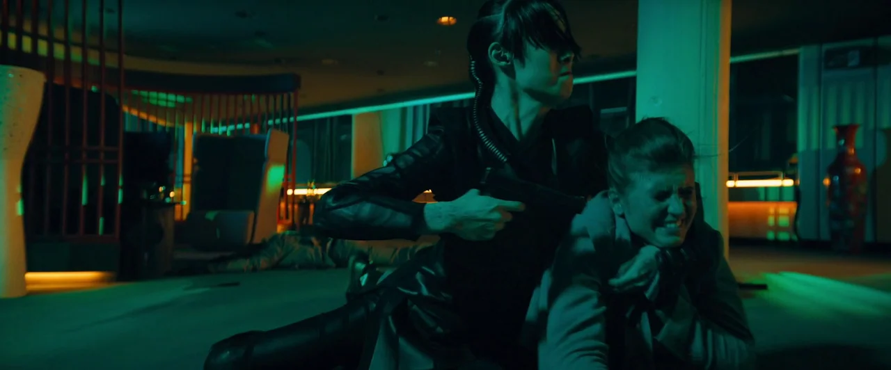 John Wick: Chapter 4 (2023) movie still: medium — A modern lounge interior is bathed in vibrant green neon lighting and warm accents. A woman in…