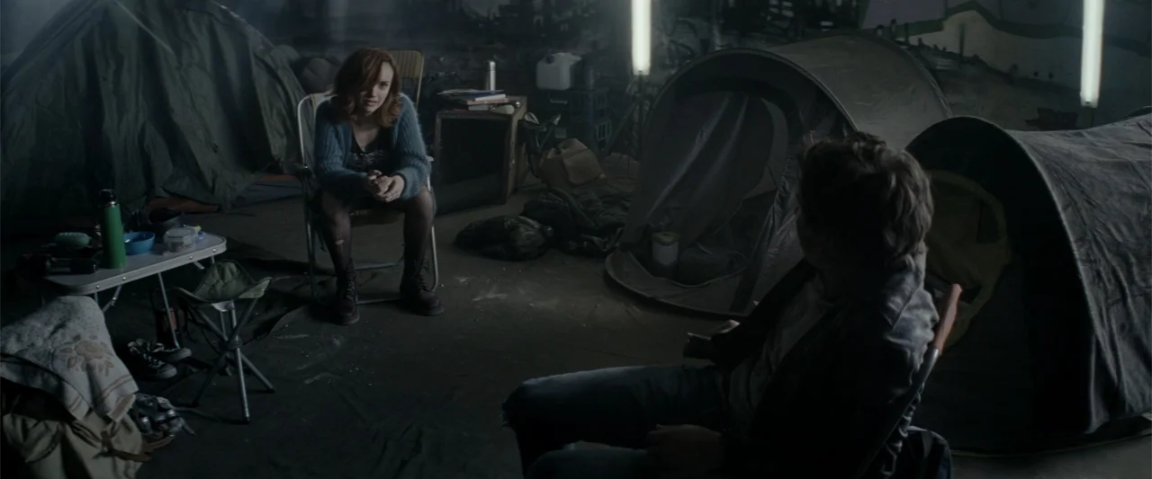 Ready Player One (2018) movie still: medium — A dark, industrial space serves as a makeshift campsite with several tents pitched indoors. A woman…