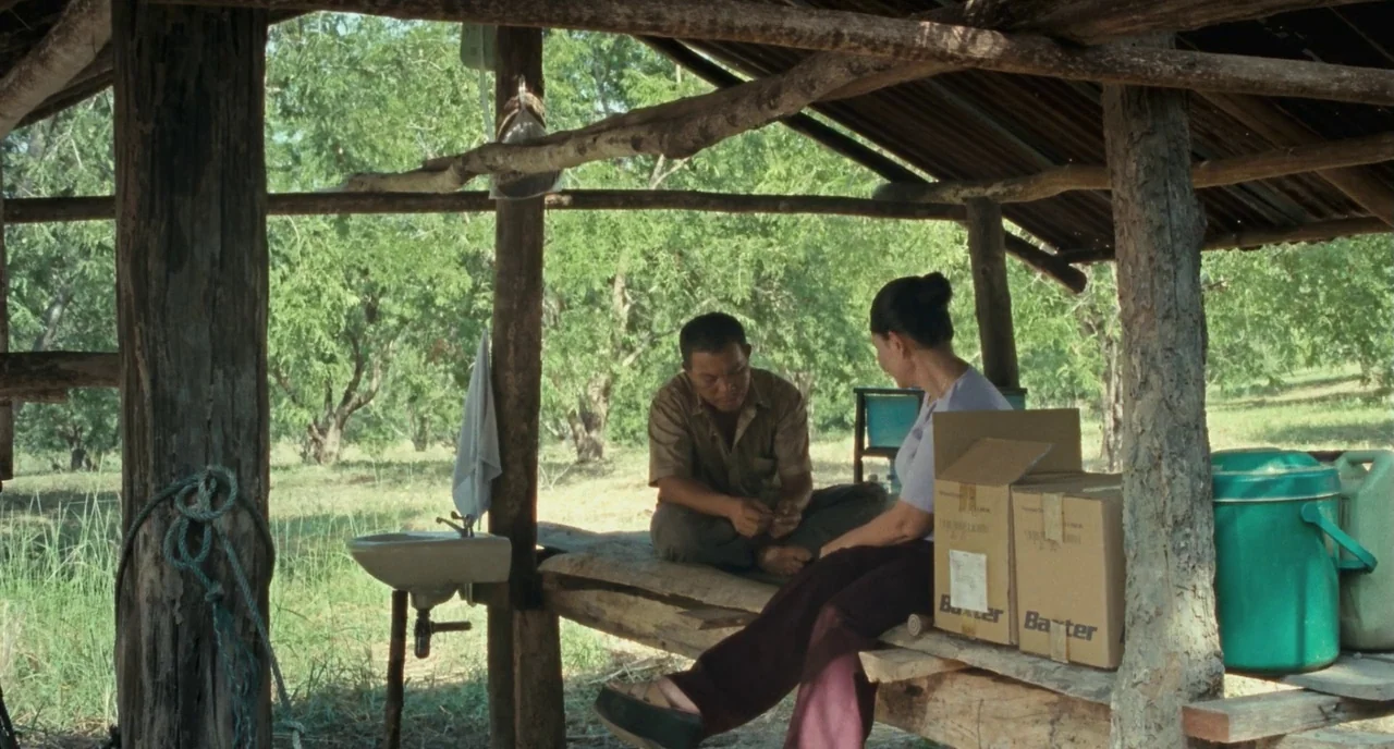 Uncle Boonme Who Can Recall His Past Lives (2010) movie still: wide — An open-air wooden structure with a corrugated metal roof stands among lush…
