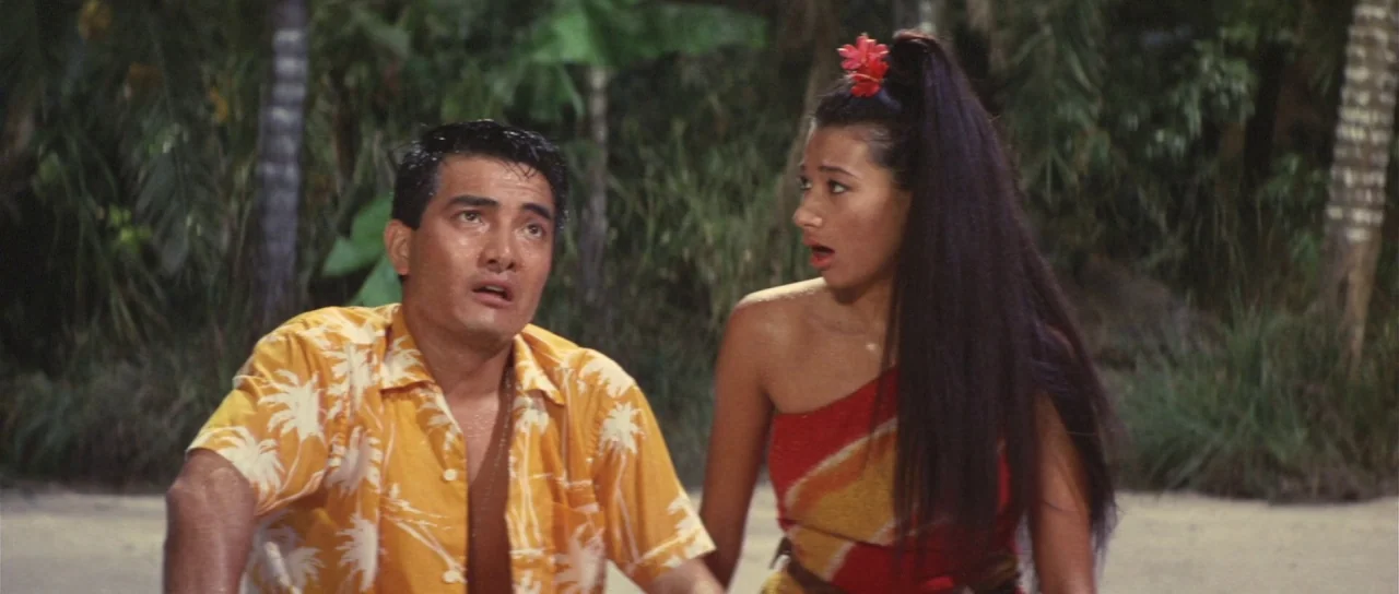Son of Godzilla (1967) movie still: medium — A dark tropical beach at night with dense jungle foliage in the background. A man and a woman in…