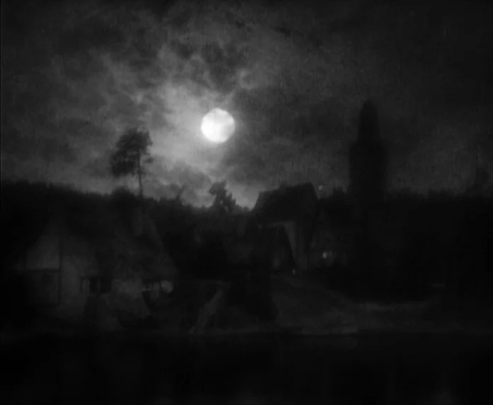 Sunrise (1927) movie still: establishing — A dark, atmospheric village sits by the water under a large glowing full moon. Clouds drift across the…
