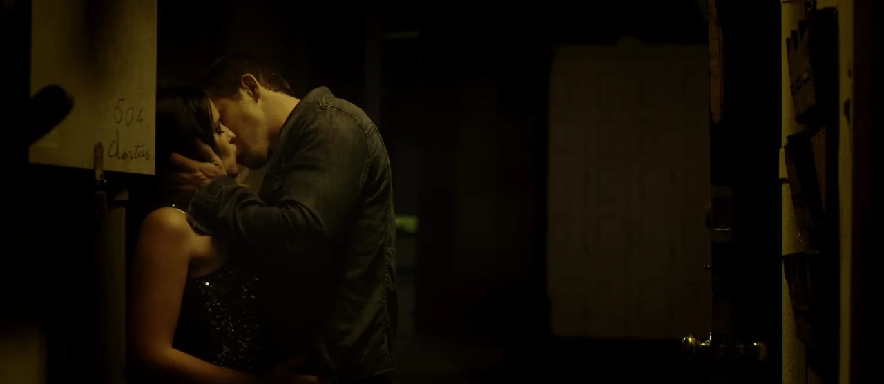 Self/less (2015) movie still: medium — A dark, cramped building entryway features a door with room number 504. A couple stands in the shadows…