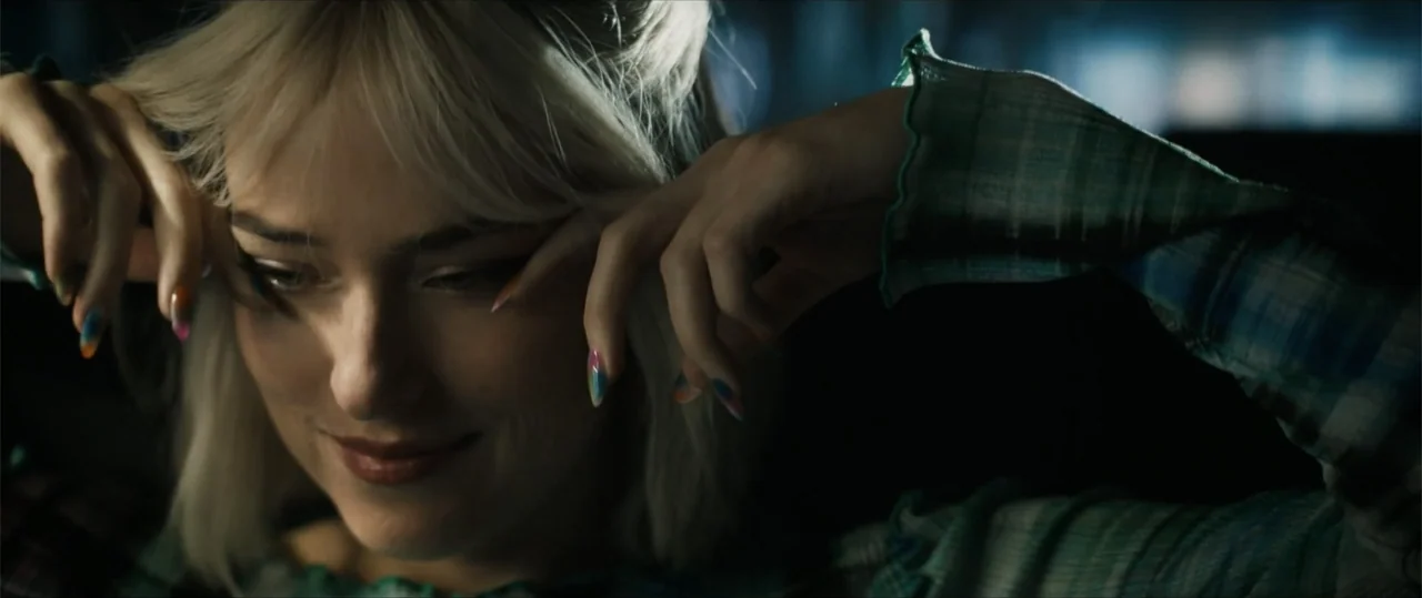 Daddio (2024) movie still: closeup — A dark vehicle interior with a person seated in the shadows. A young woman with blonde hair holds her hands by…