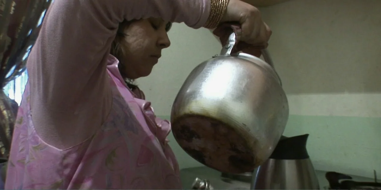 Silencing the Song: An Afghan Fallen Star (2011) movie still: medium — A domestic space with pale green walls and a metal surface. A woman in a pink…