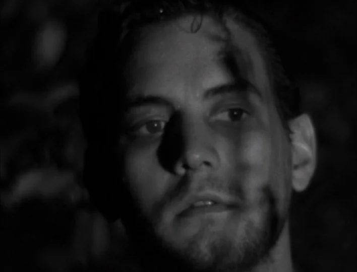 Tales from the Gimli Hospital (1988) movie still: closeup — The face of a young man is illuminated against a dark, indistinct outdoor background.…