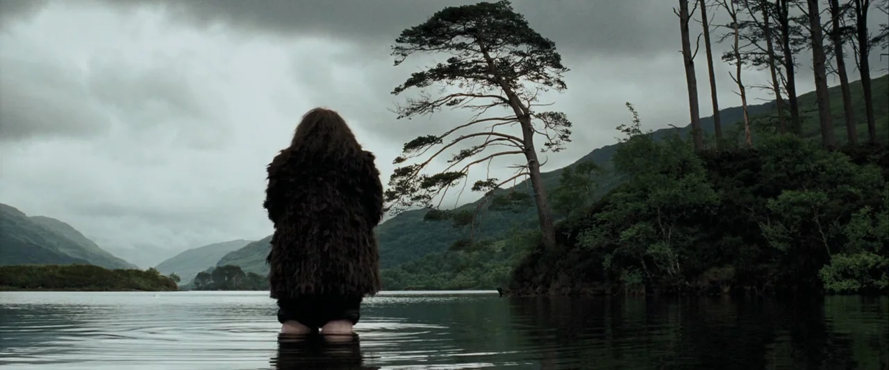 Harry Potter and the Prisoner of Azkaban (2004) movie still: fullbody — A person stands in the middle of a calm, dark lake under a cloudy sky. The…
