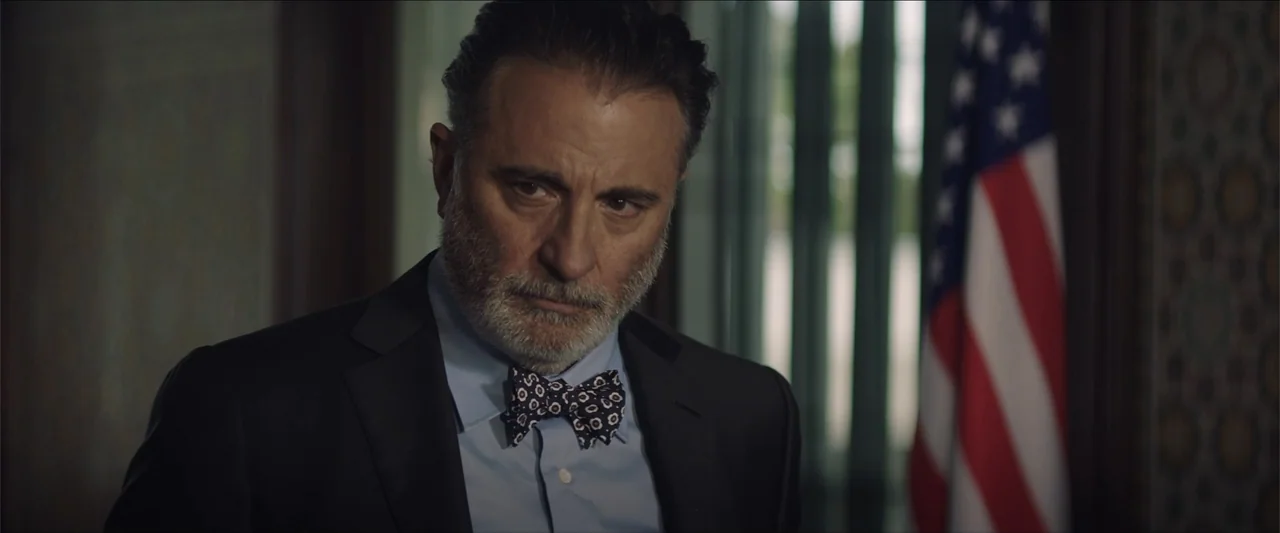 Redemption Day (2021) movie still: medium — A dimly lit office features a visible American flag in the blurred background. A mature man in a suit…