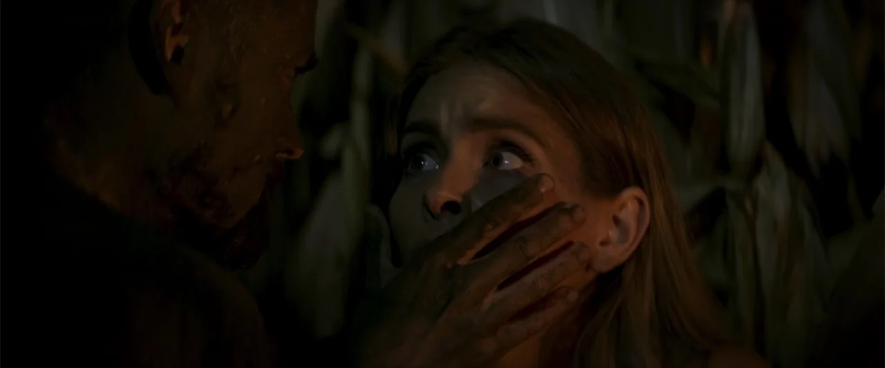 Treblinka's Last Witness (2012) movie still: closeup — A dark night setting within a dense cornfield at close range. A man presses a dirty hand over…