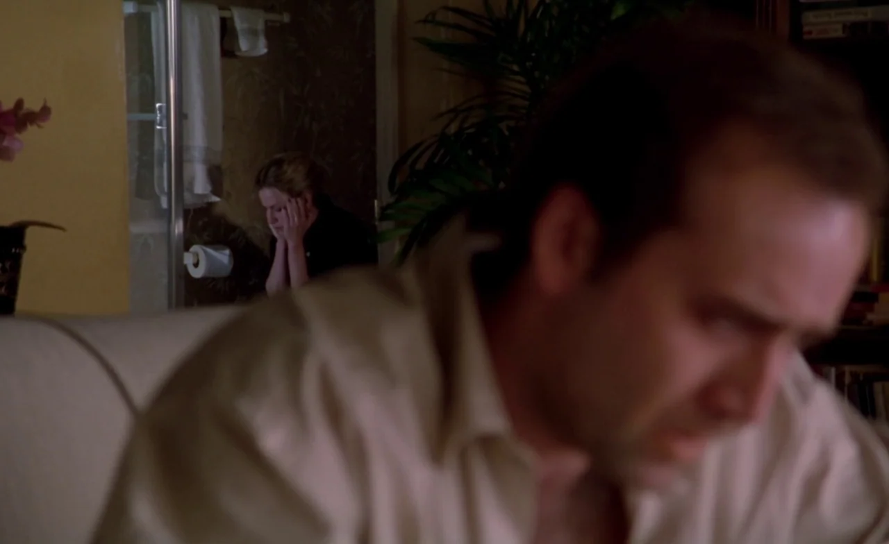 Leaving Las Vegas (1995) movie still: medium — A dimly lit room contains a man blurred in the immediate foreground. In the distant background, a…