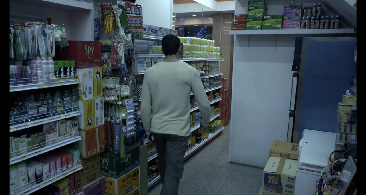Ninja: Shadow of a Tear (2013) movie still: medium — A cramped convenience store aisle is filled with stacked products and fluorescent light…