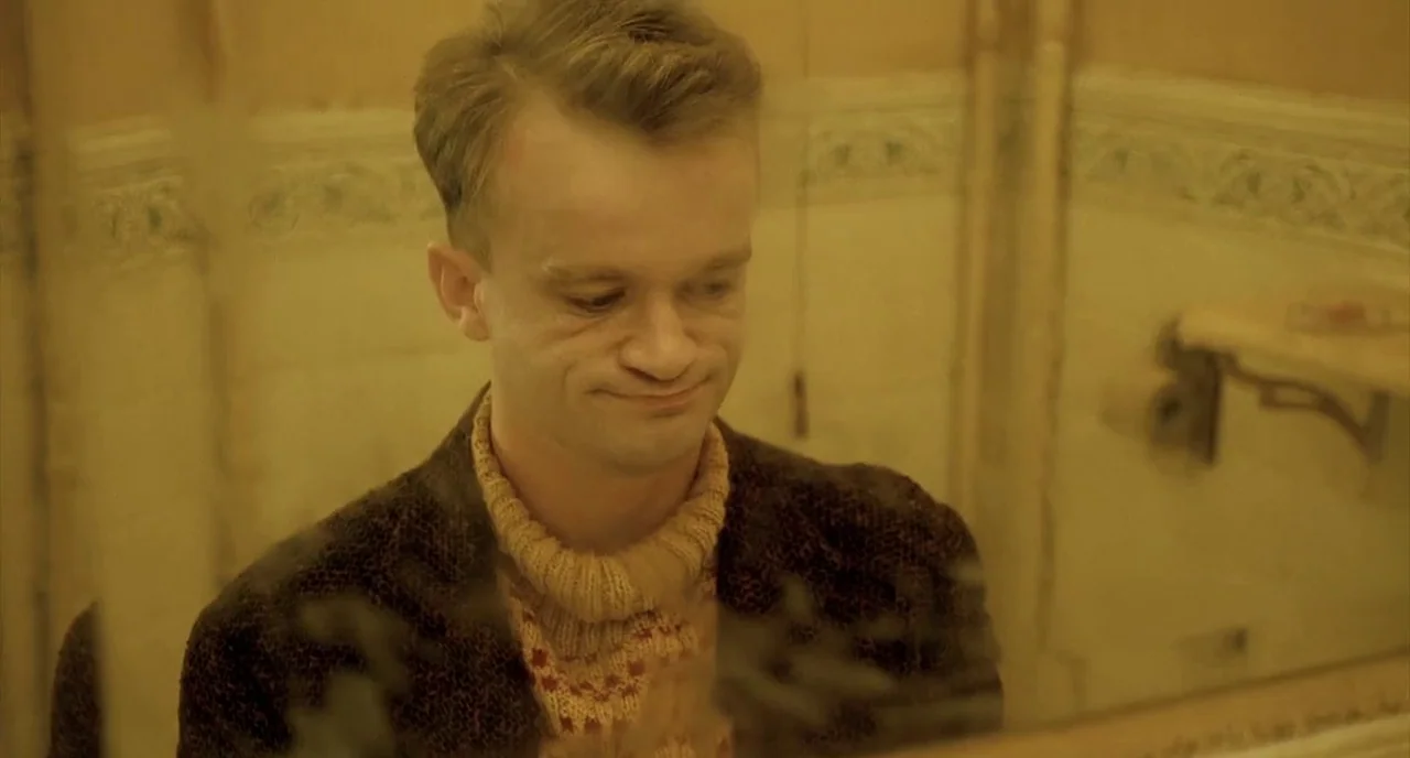 Delicatessen (1991) movie still: closeup — The reflection of a man is visible in a slightly blurred bathroom mirror. He stares forward while wearing…