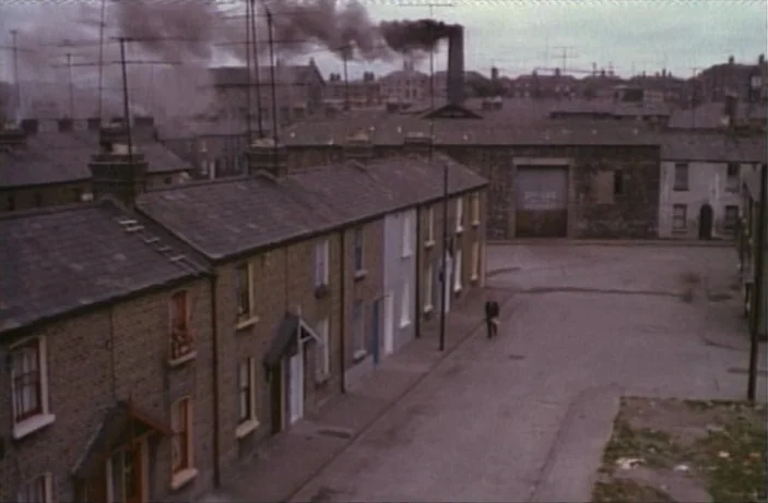 Quackser Fortune Has a Cousin in the Bronx (1970) movie still: wide — A rows of terraced brick houses line a quiet, overcast street in an industrial…