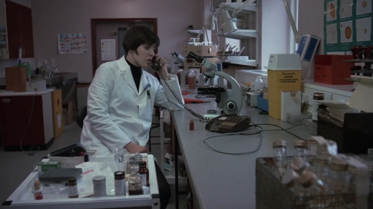 The Lair of the White Worm (1988) movie still: medium — A sterile laboratory workspace filled with glass vials and scientific equipment on grey…