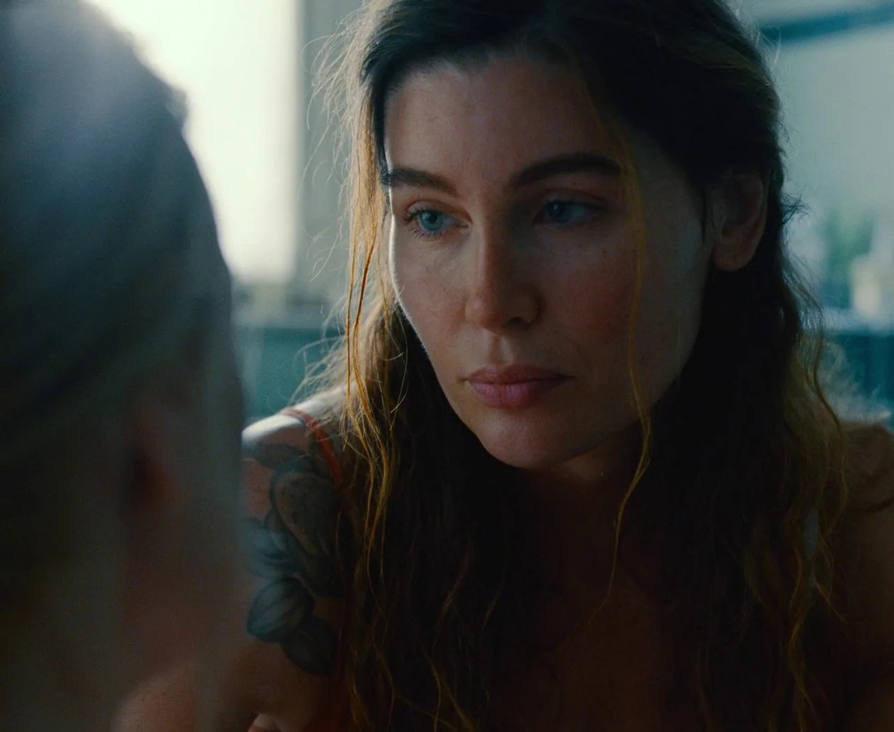 Monica (2022) movie still: An intimate, quiet moment of connection captured in a close-up. The subject, softly backlit by natural window light,…