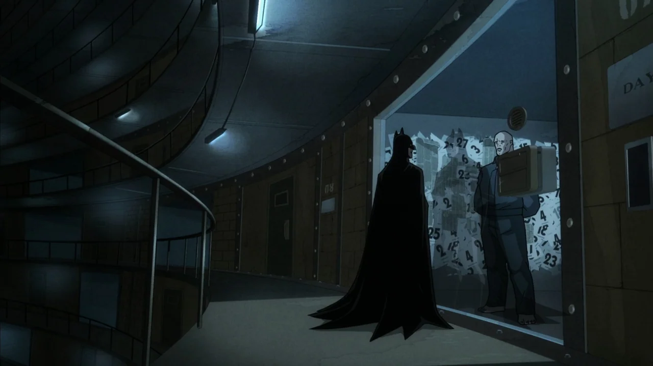 Batman: The Long Halloween, Part Two (2021) movie still: wide — A curved prison corridor features metal walls with numbers and a glass cell block.…