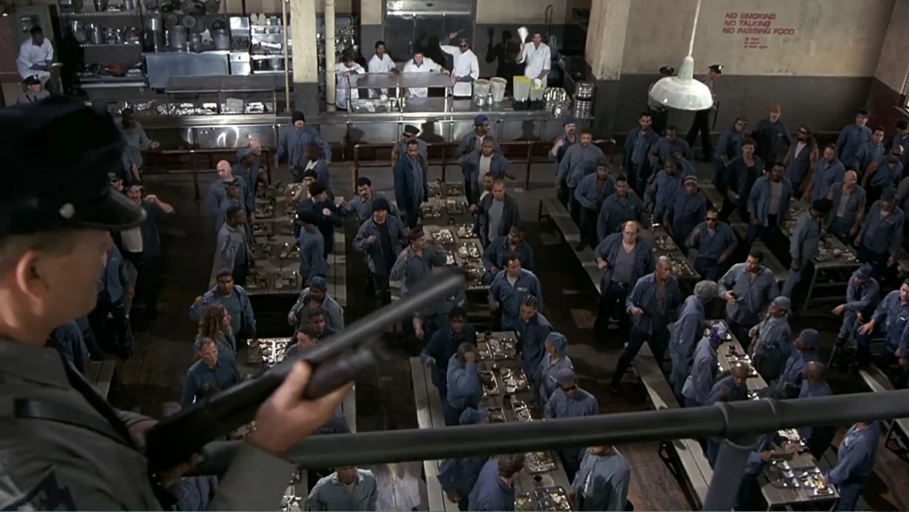 Naked Gun 33⅓: The Final Insult (1994) movie still: wide — A crowded prison dining hall features long tables with many inmates in blue uniforms. A…