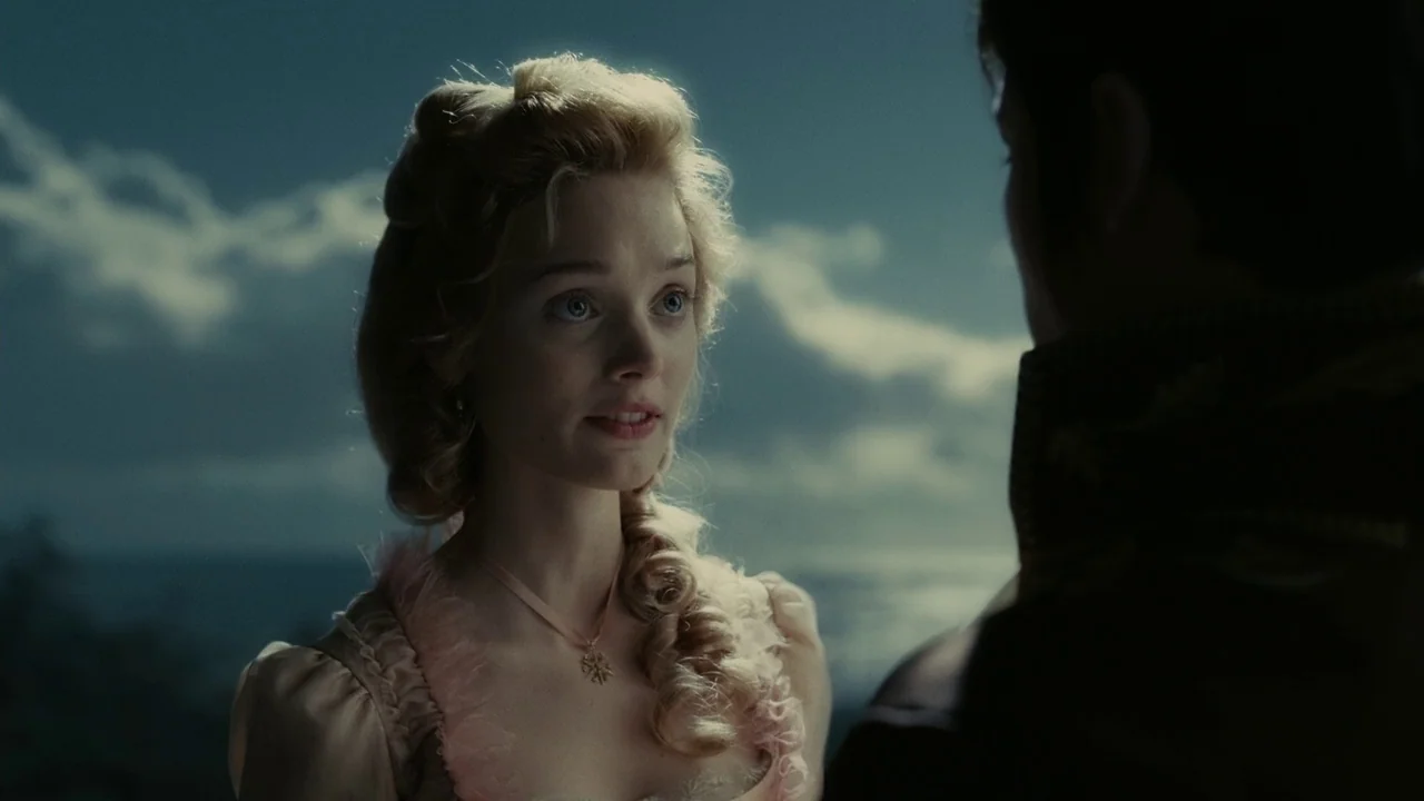 Dark Shadows (2012) movie still: medium — A coastal setting with a cloudy sky and dark water visible in the background. A woman in a pink dress…
