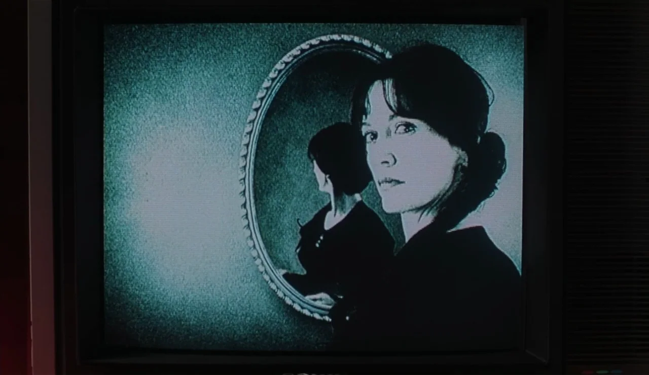The Ring (2002) movie still: medium — A low-resolution image shown on a television screen displays a woman looking into a mirror. Her reflected…