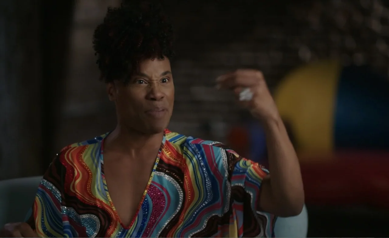 Let the Canary Sing (2023) movie still: medium — A dark, dimly lit lounge with blurred colorful shapes in the background. A man in a vibrant kaftan…