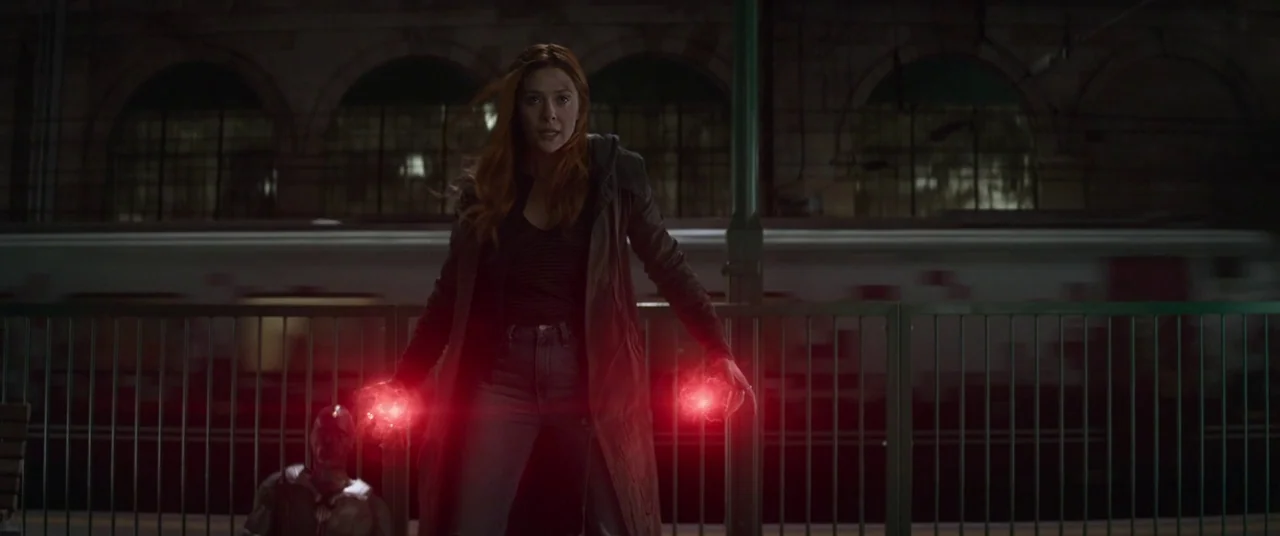 Avengers: Infinity War (2018) movie still: fullbody — An open train platform at night with a blurred train passing in the background. A woman in a…