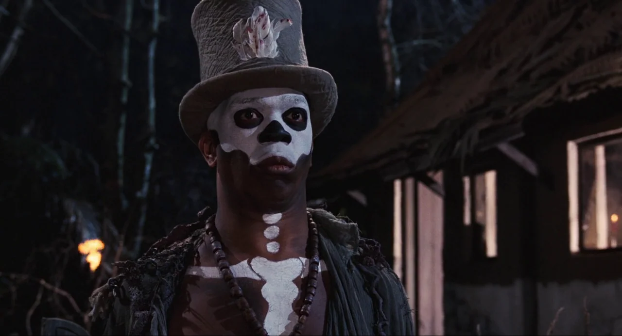 Live and Let Die (1973) movie still: closeup — A man stands outdoors at night wearing theatrical skull makeup and a top hat. He stares blankly into…
