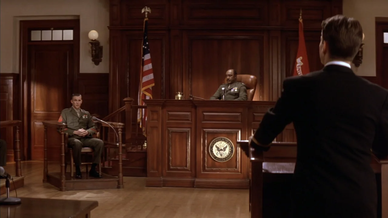 A Few Good Men (1992) movie still: medium — A wood-paneled military courtroom contains a judge, a witness, and a lawyer. A marine sits in the…