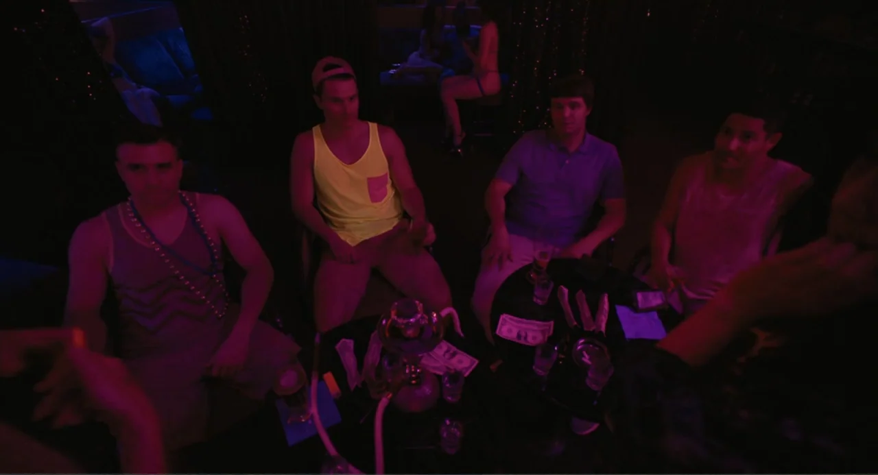 Mona Lisa and the Blood Moon (2022) movie still: medium — A dark, neon-lit lounge area features a small round table cluttered with drinks and cash.…