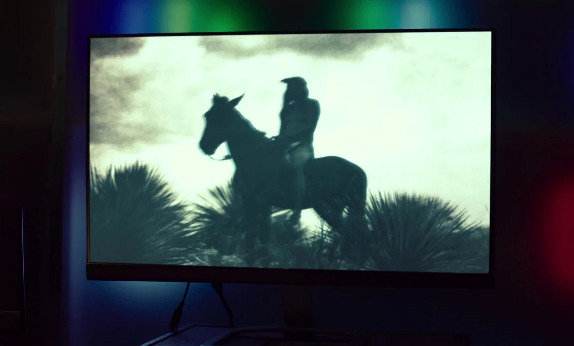 High Life (2018) movie still: medium — A computer monitor screen displays a black and white film of a rider. The figure on horseback travels through…