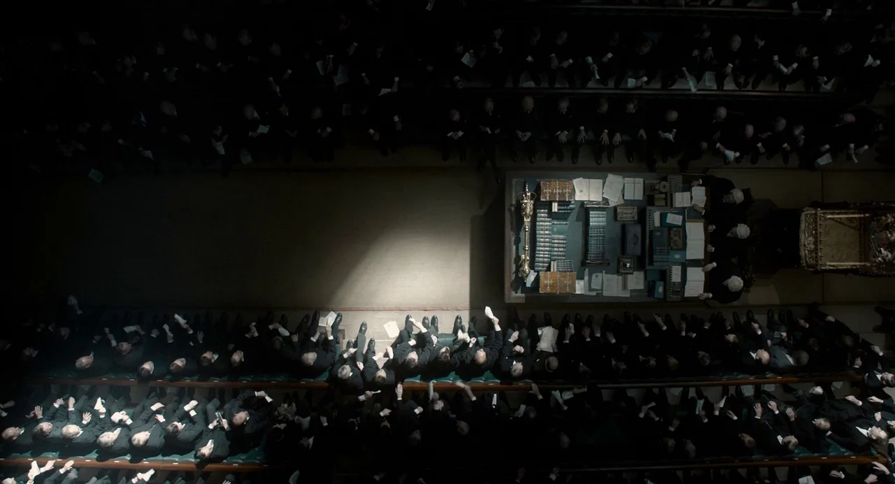 Darkest Hour (2017) movie still: establishing — A top-down view of a historic legislative chamber with rows of dark leather benches. Many people in…